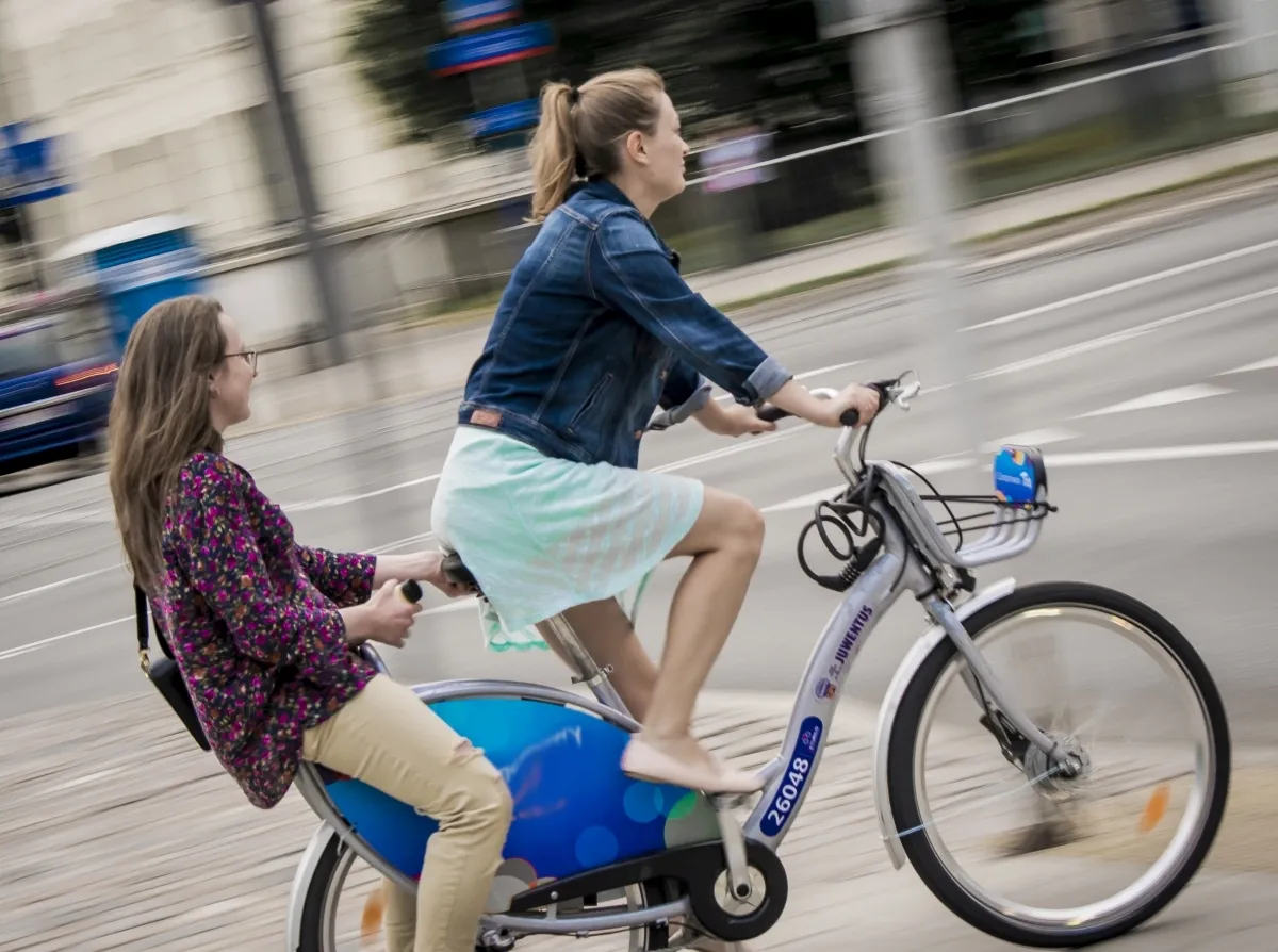 Two young women sharing a city bicycle in motion blur